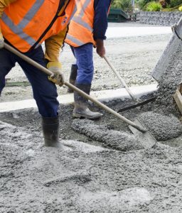Concreter spreading and levelling fresh concrete using a rake and screed board