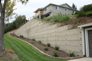 Tall concrete retaining wall supporting a sloping block